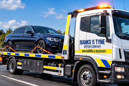 Flatbed recovery truck with a car loaded on the bed